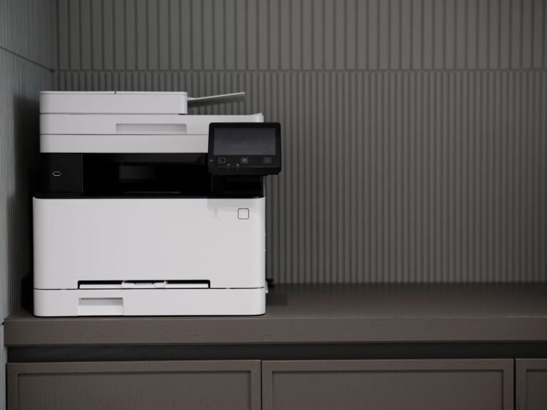 A sleek, modern printer situated on a minimalist office desk with a textured background.