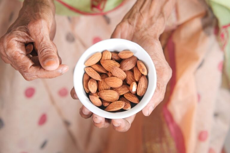 Senior hands holding a bowl of almonds, symbolizing health and nourishment.
