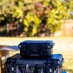 Black protective cases for photography gear outdoors on a sunny day.