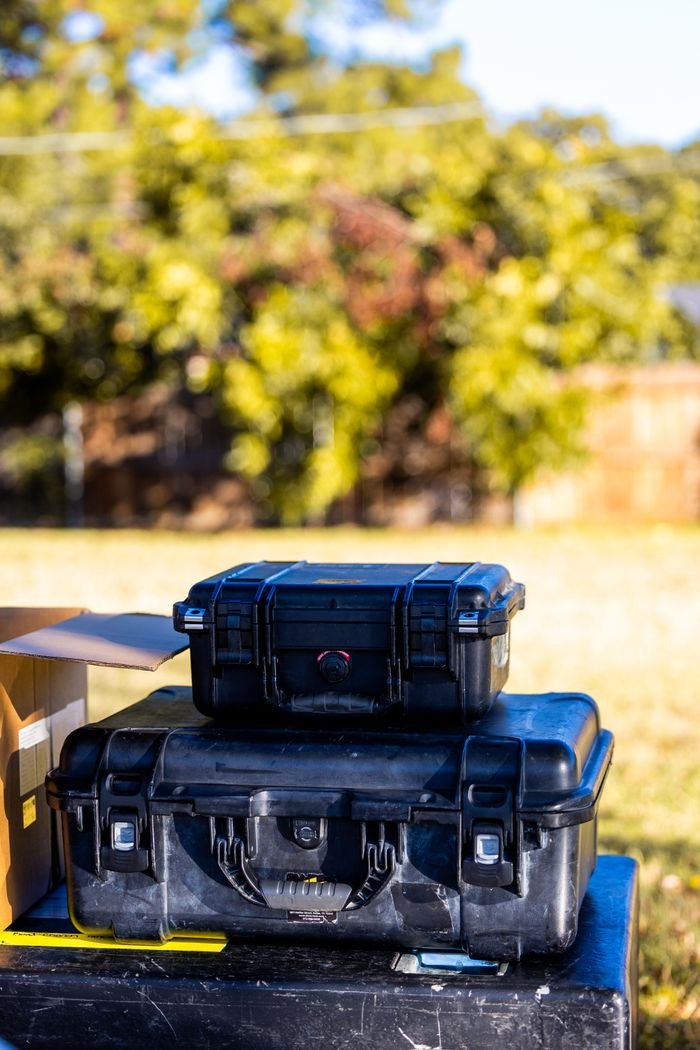 Black protective cases for photography gear outdoors on a sunny day.