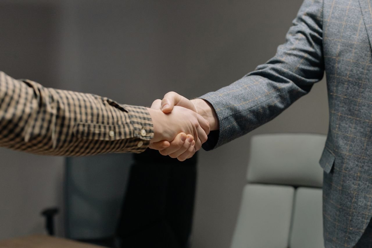 Close-up of two professionals shaking hands in an office, symbolizing successful business dealings.